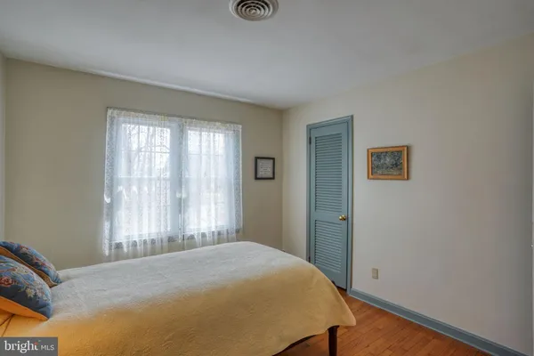 a bedroom with a bed a dresser and next to a window