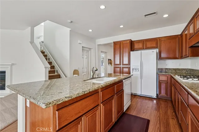 a kitchen with stainless steel appliances granite countertop a refrigerator a microwave oven a dining table and chairs with wooden floor