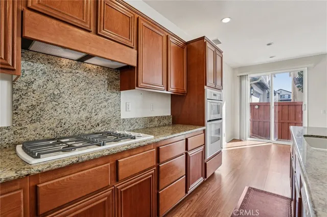 a kitchen with stainless steel appliances granite countertop a refrigerator a stove and a sink with wooden floor