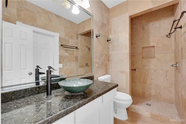 a bathroom with a granite countertop sink a toilet and shower