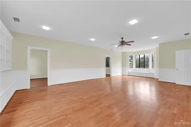 a view of empty room with wooden floor and windows
