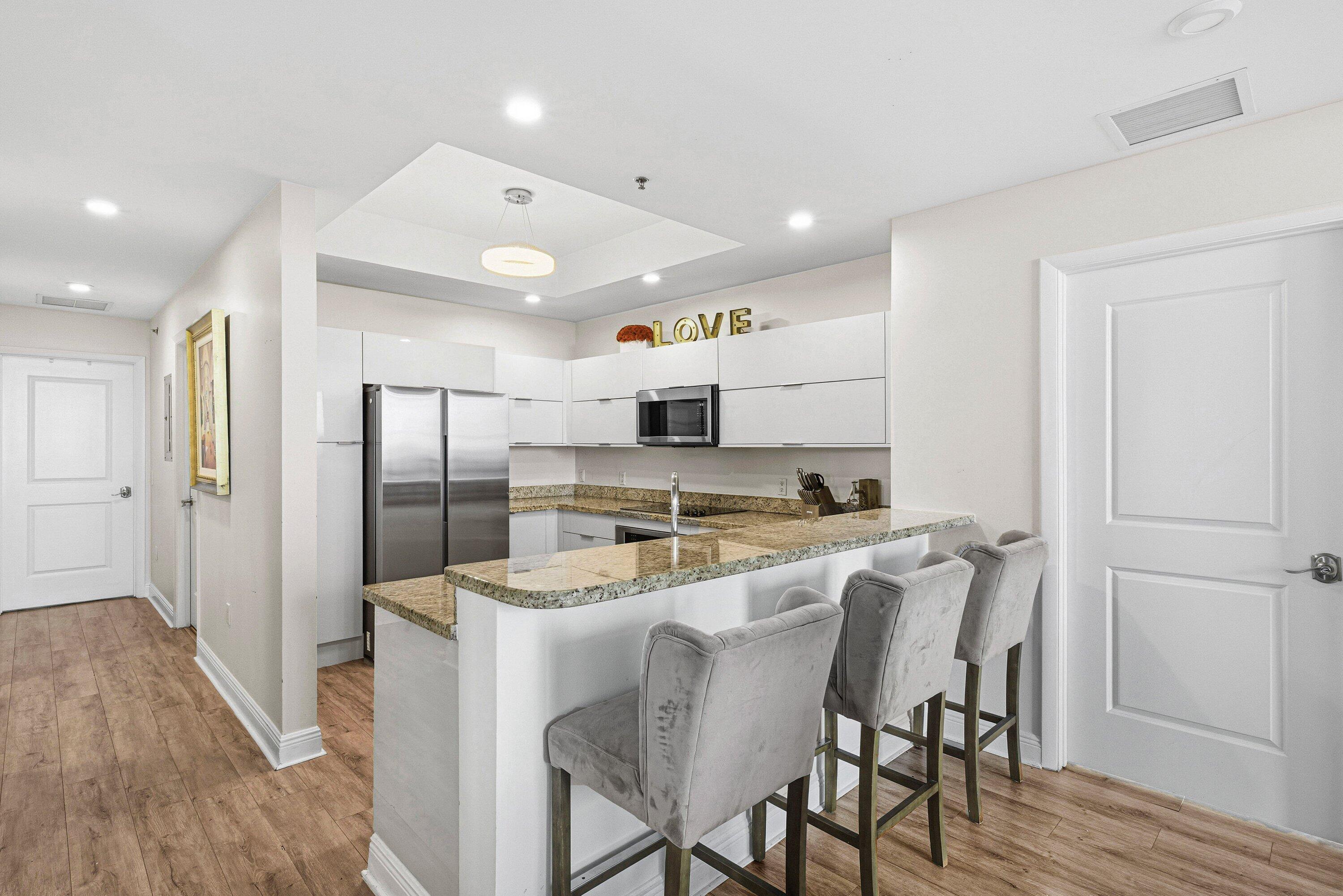 2641 North Flamingo Road, Unit 2701N Sunrise, FL 33323 - Photo 7 of 38 a kitchen with stainless steel appliances granite countertop a refrigerator a stove top oven and a dining table with wooden floor