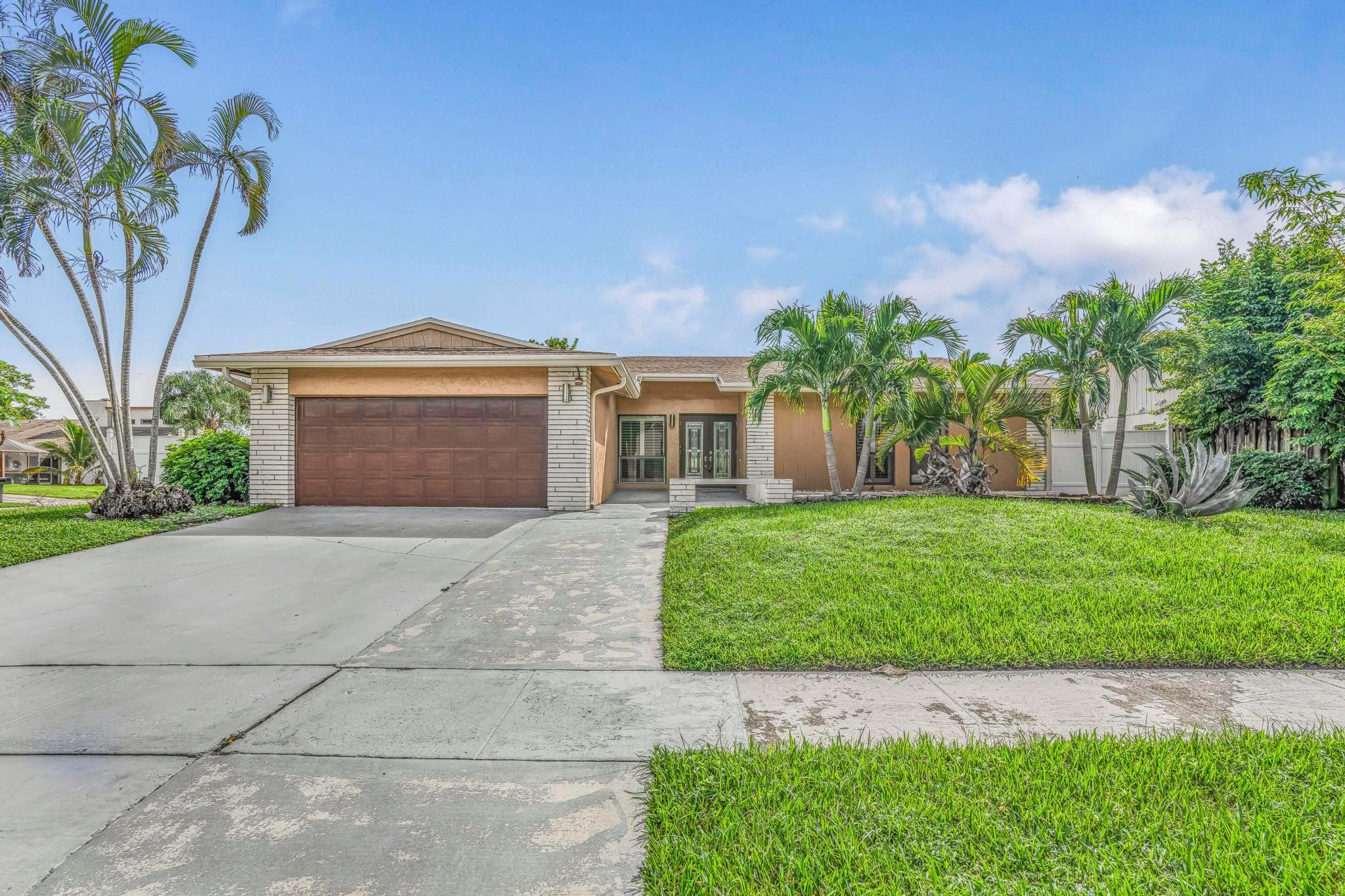 3374 Northwest 27th Terrace Boca Raton, FL 33434 - Photo 6 of 33 a front view of a house with a garden and yard
