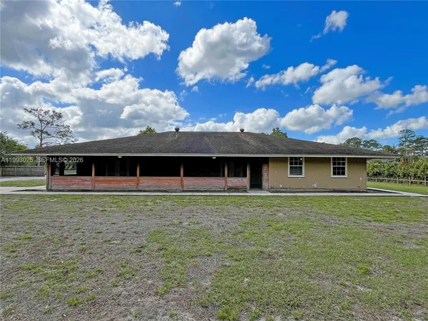 a front view of house with yard and trees in the background