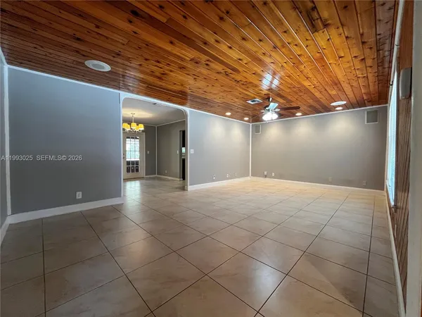 a view of an empty room with window and chandelier