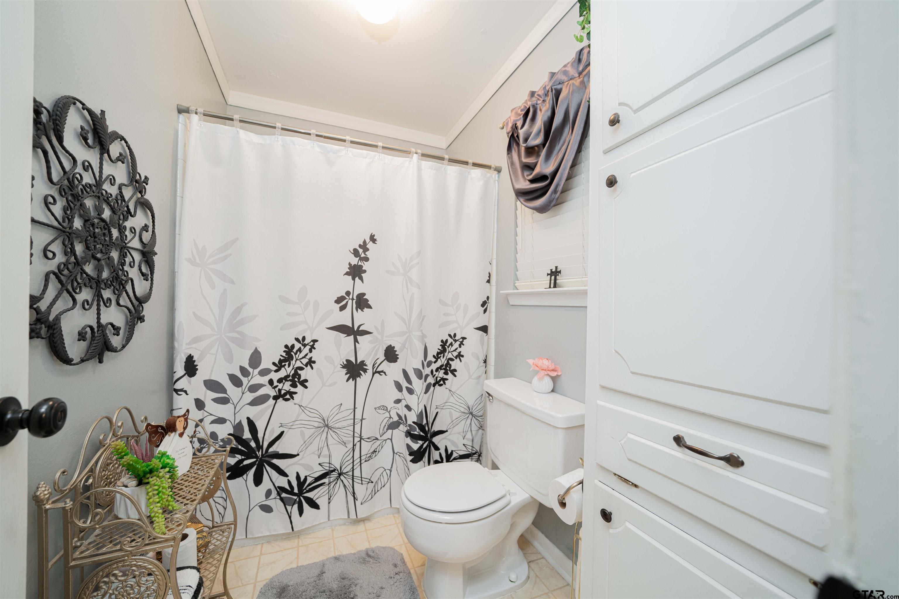 209 Cheryl Street Longview, TX 75604 - Photo 17 of 41 a bathroom with a shower curtain and a toilet