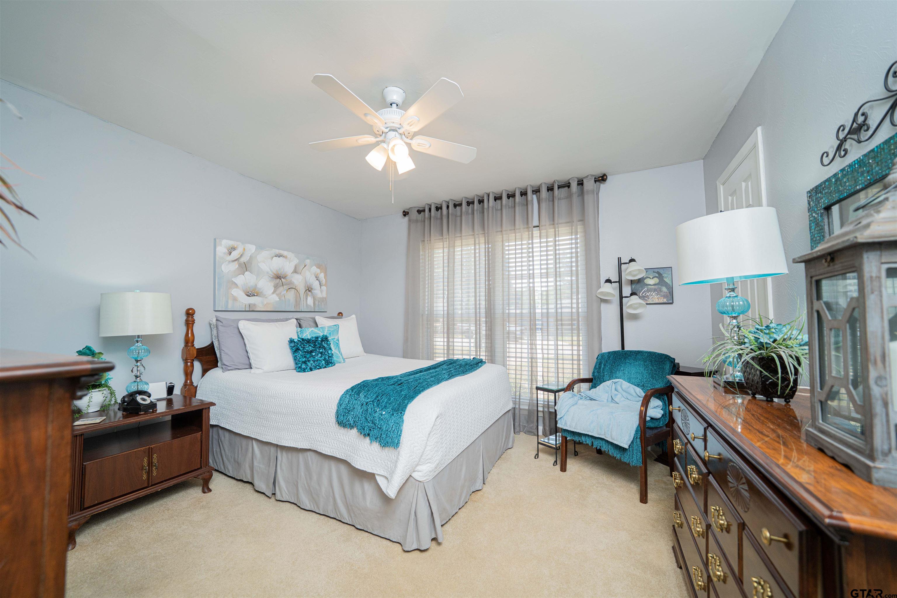 209 Cheryl Street Longview, TX 75604 - Photo 18 of 41 a spacious bedroom with a bed a couch and a chandelier