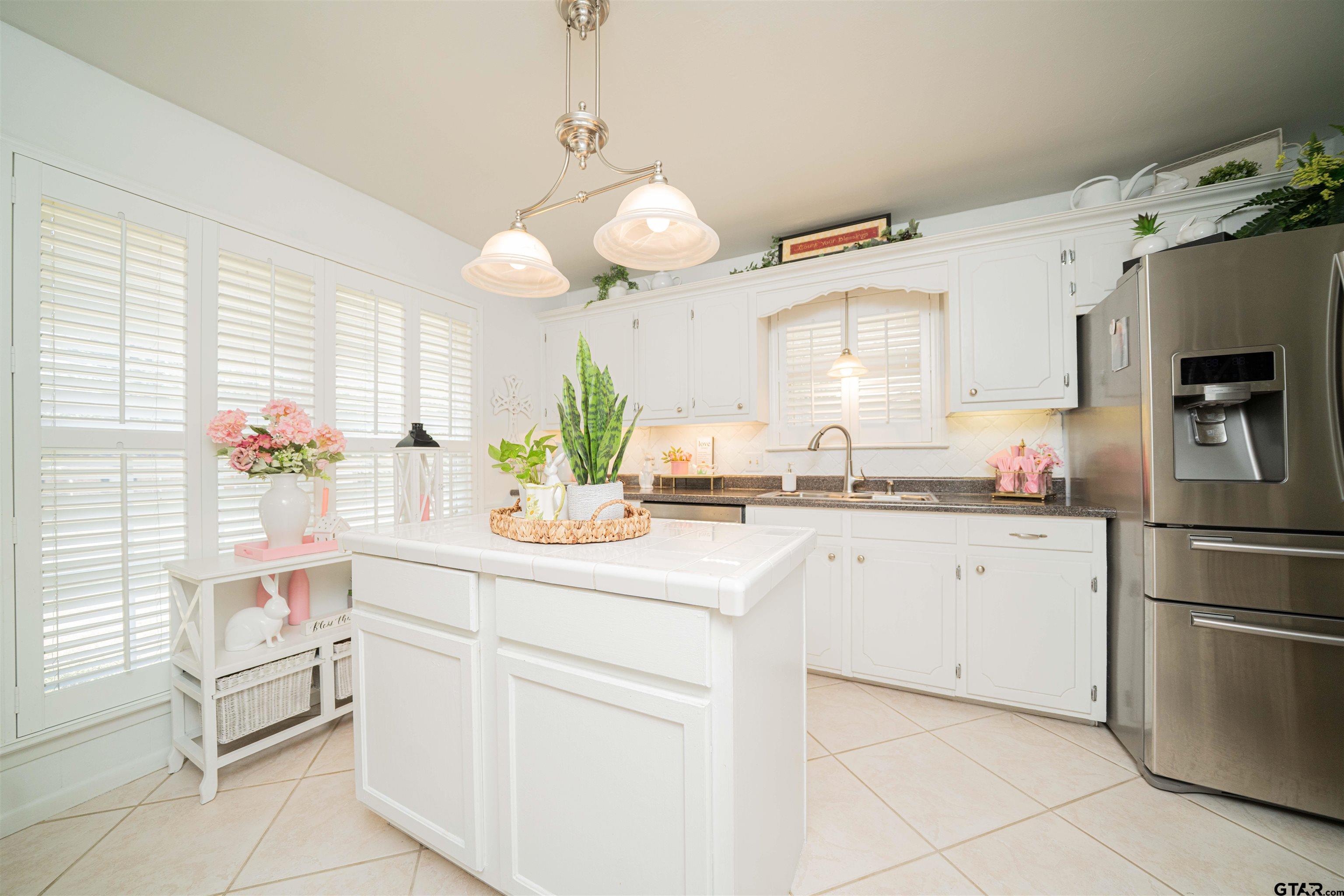 209 Cheryl Street Longview, TX 75604 - Photo 5 of 41 a kitchen with white cabinets and chandelier