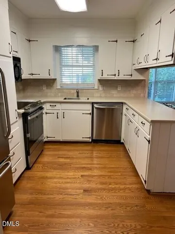 a kitchen with stainless steel appliances granite countertop a stove a sink and white cabinets