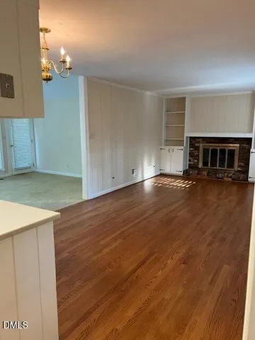 an empty room with wooden floor and a kitchen view