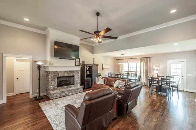 a open dining room with stainless steel appliances kitchen island granite countertop a dining table chairs and a refrigerator a mirror with wooden floors