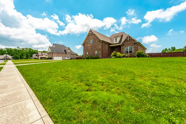 a view of a house with a big yard and large trees