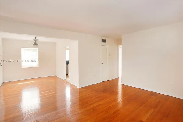 a view of an empty room with wooden floor and a window