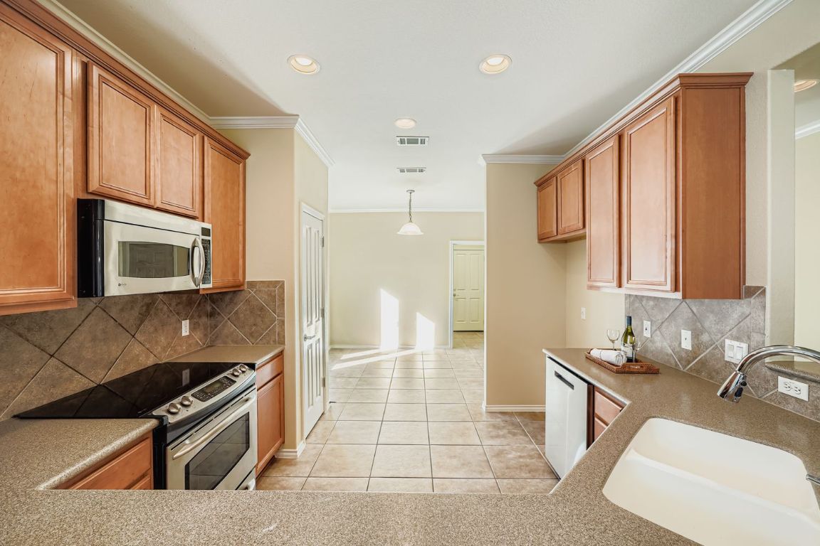 307 Mill Pond Path Georgetown, TX 78633 - Photo 12 of 26 Kitchen featuring crown molding, tasteful backsplash, stainless steel appliances.