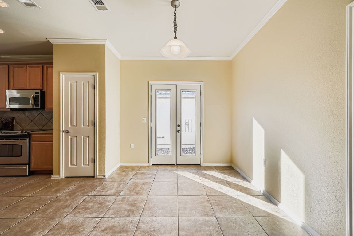 307 Mill Pond Path Georgetown, TX 78633 - Photo 13 of 26 French doors off the eat in kitchen, light tile patterned flooring, and ornamental molding