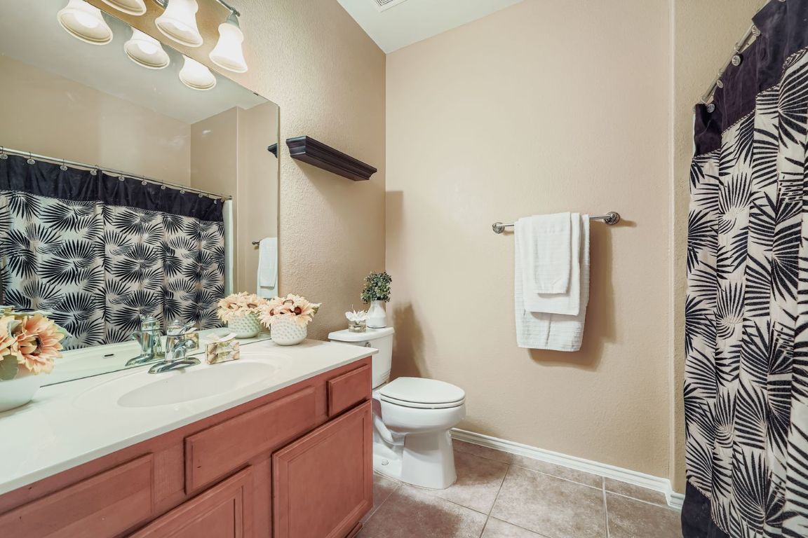 307 Mill Pond Path Georgetown, TX 78633 - Photo 20 of 26 Bathroom featuring vanity, light tile patterned floors, curtained shower, and a textured wall