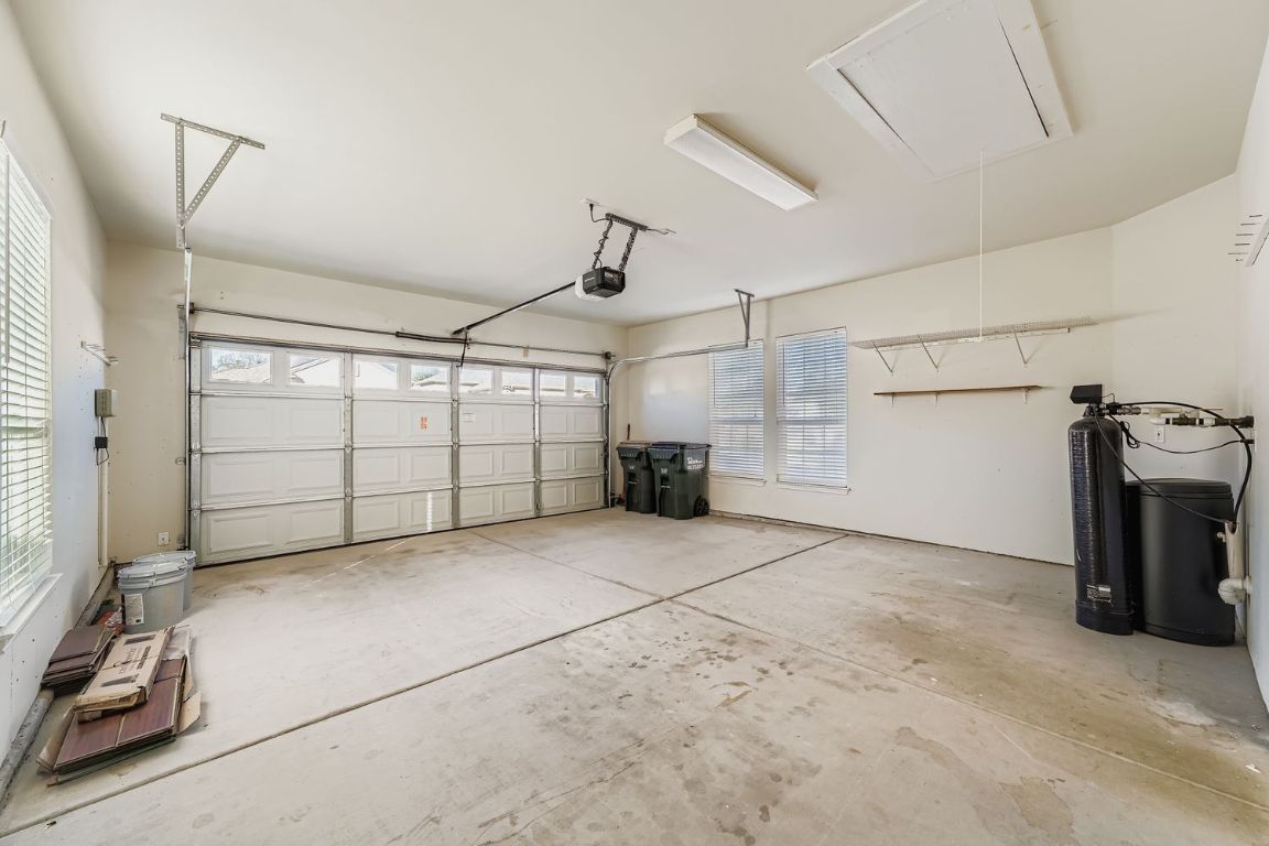 307 Mill Pond Path Georgetown, TX 78633 - Photo 24 of 26 Garage with a garage door opener, water softener, and three windows. Extra wood for the flooring and paint.