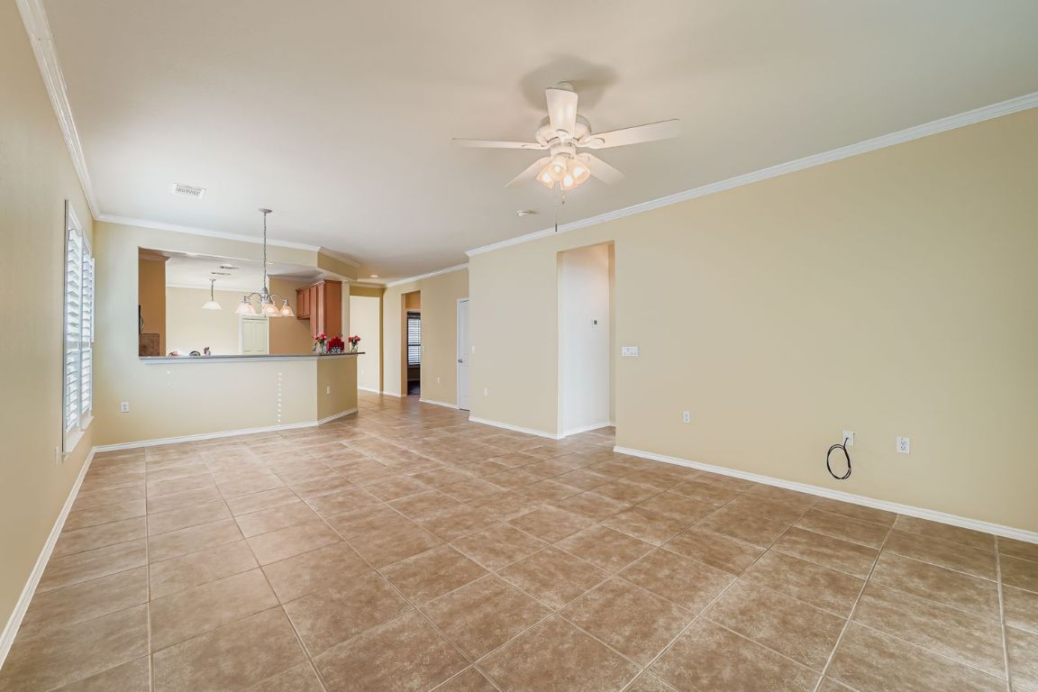 307 Mill Pond Path Georgetown, TX 78633 - Photo 7 of 26 Family oom featuring ornamental molding, a chandelier for a dining room table. a ceiling fan, and light tile patterned floors.