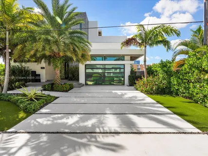 a front view of a house with a yard and potted plants