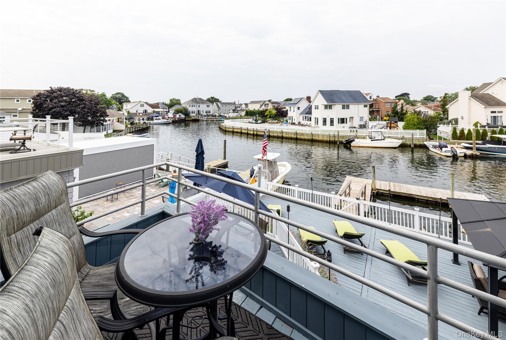 2590 Riverside Drive Wantagh, NY 11793 - Photo 21 of 27 Waterfront deck featuring a gray finish, aluminum railings, and direct water access with multiple docks