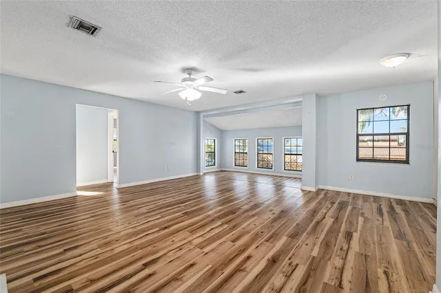 a view of an empty room with window and wooden floor