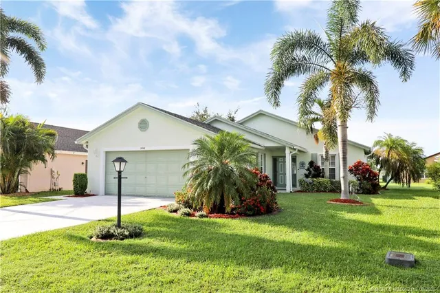 a palm tree sitting in front of a house with a big yard