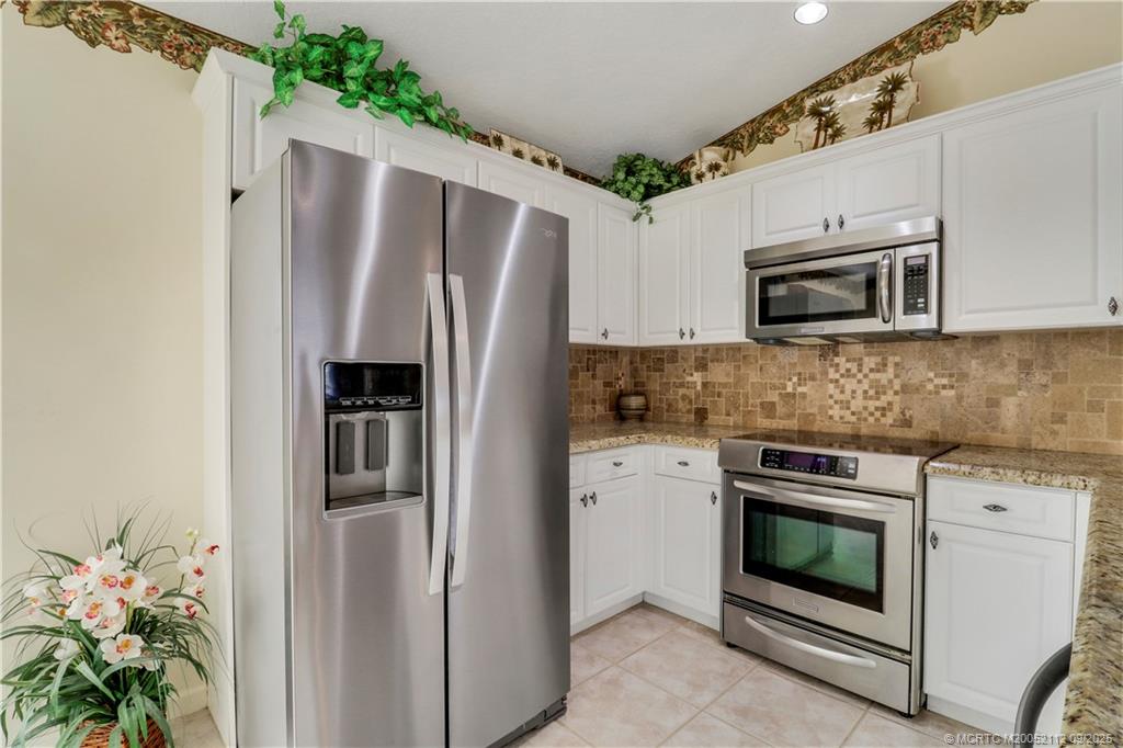 2698 Southwest Versailles Terrace Stuart, FL 34997 - Photo 16 of 29 a kitchen with granite countertop white cabinets and stainless steel appliances