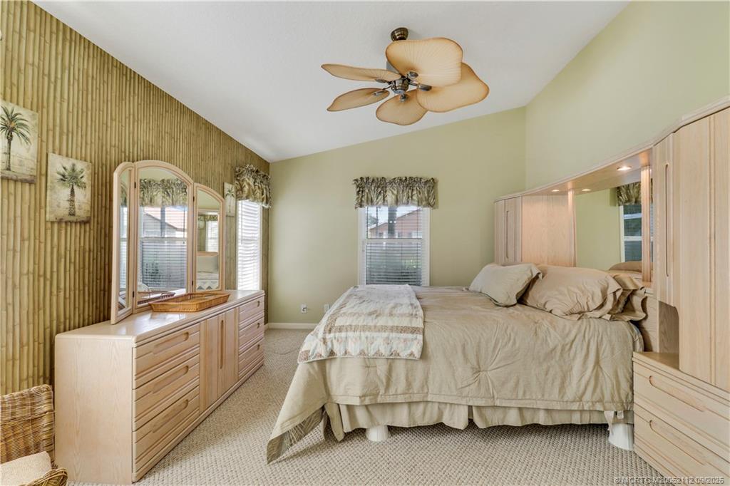 2698 Southwest Versailles Terrace Stuart, FL 34997 - Photo 18 of 29 a bedroom with a bed a chandelier and a large mirror on the dresser