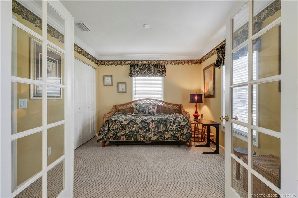 2698 Southwest Versailles Terrace Stuart, FL 34997 - Photo 24 of 29 a bedroom with a bed and a cabinets next to a window