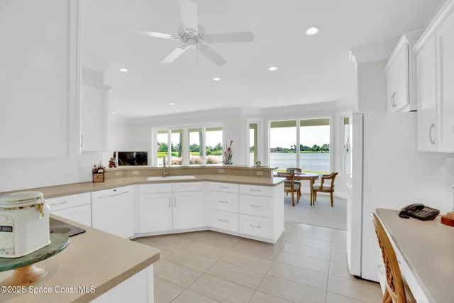 a large kitchen with kitchen island a sink white cabinets and appliances
