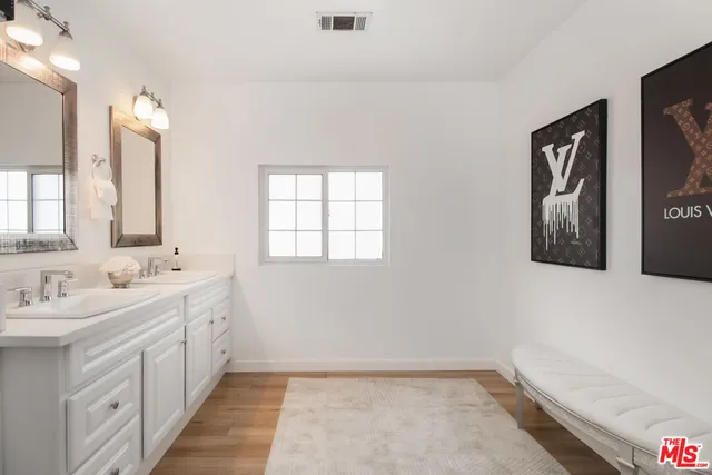 a bathroom with double vanity sink a mirror and a bathtub