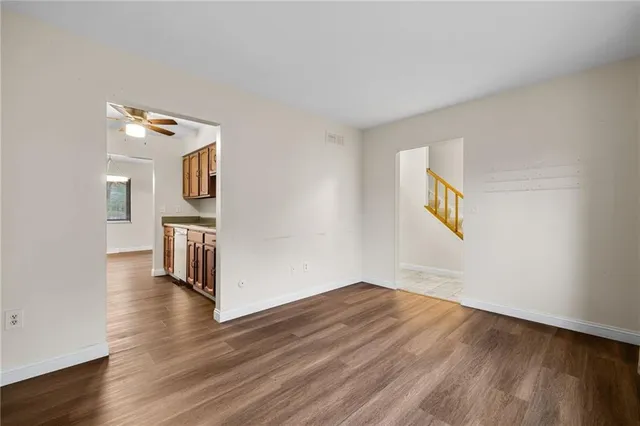 a view of a hallway with wooden floor and a bathroom