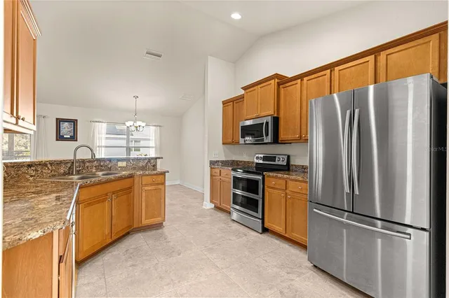 a kitchen with stainless steel appliances granite countertop a refrigerator stove top oven and sink