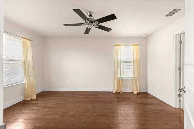 a view of empty room with wooden floor and fan