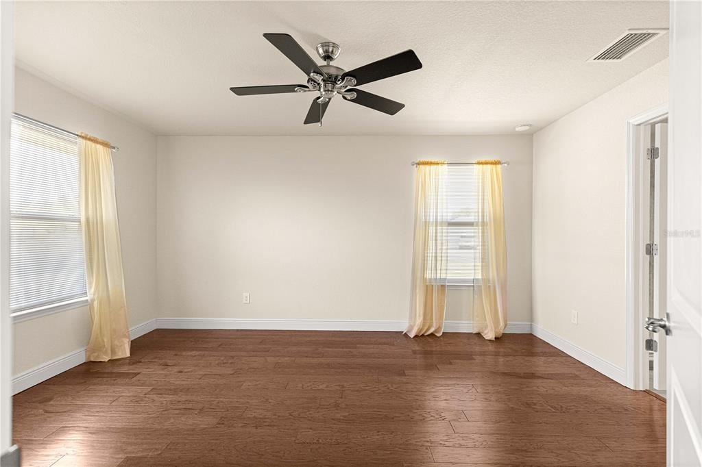 4401 Southwest 62nd Loop Ocala, FL 34474 - Photo 19 of 53 an empty room with wooden floor a ceiling fan and windows