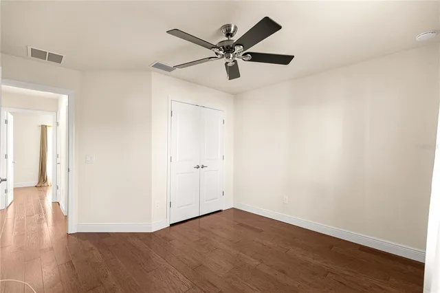 an empty room with wooden floor fan and windows