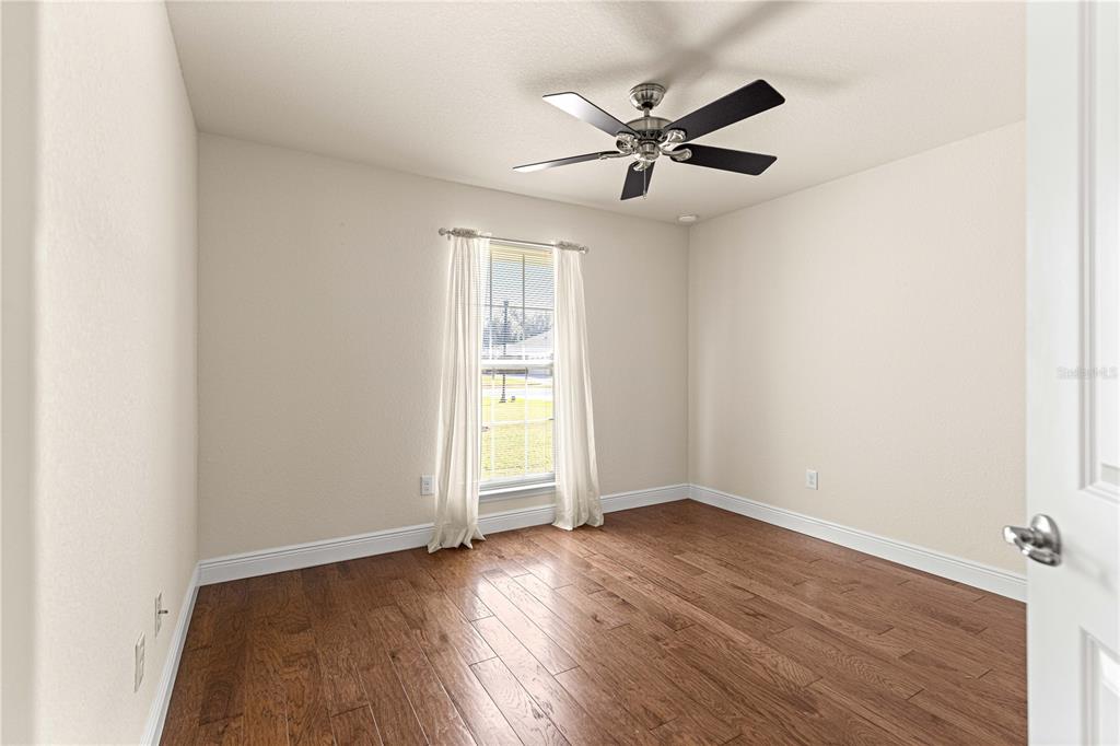4401 Southwest 62nd Loop Ocala, FL 34474 - Photo 33 of 53 an empty room with wooden floor chandelier fan and windows