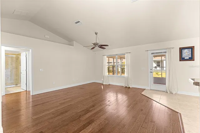 an empty room with wooden floor chandelier and windows