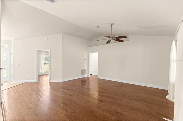 an empty room with a hardwood and ceiling fan