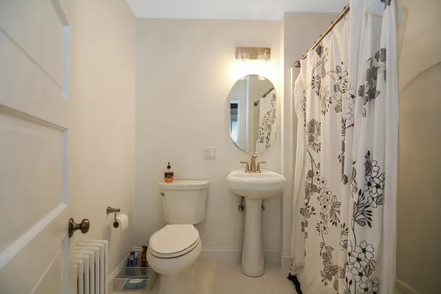 a bathroom with a toilet sink and shower curtain