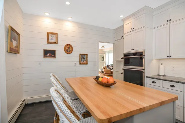 a kitchen with stainless steel appliances a stove a refrigerator a white table and chairs