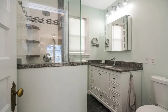 a bathroom with a granite countertop sink mirror vanity and toilet