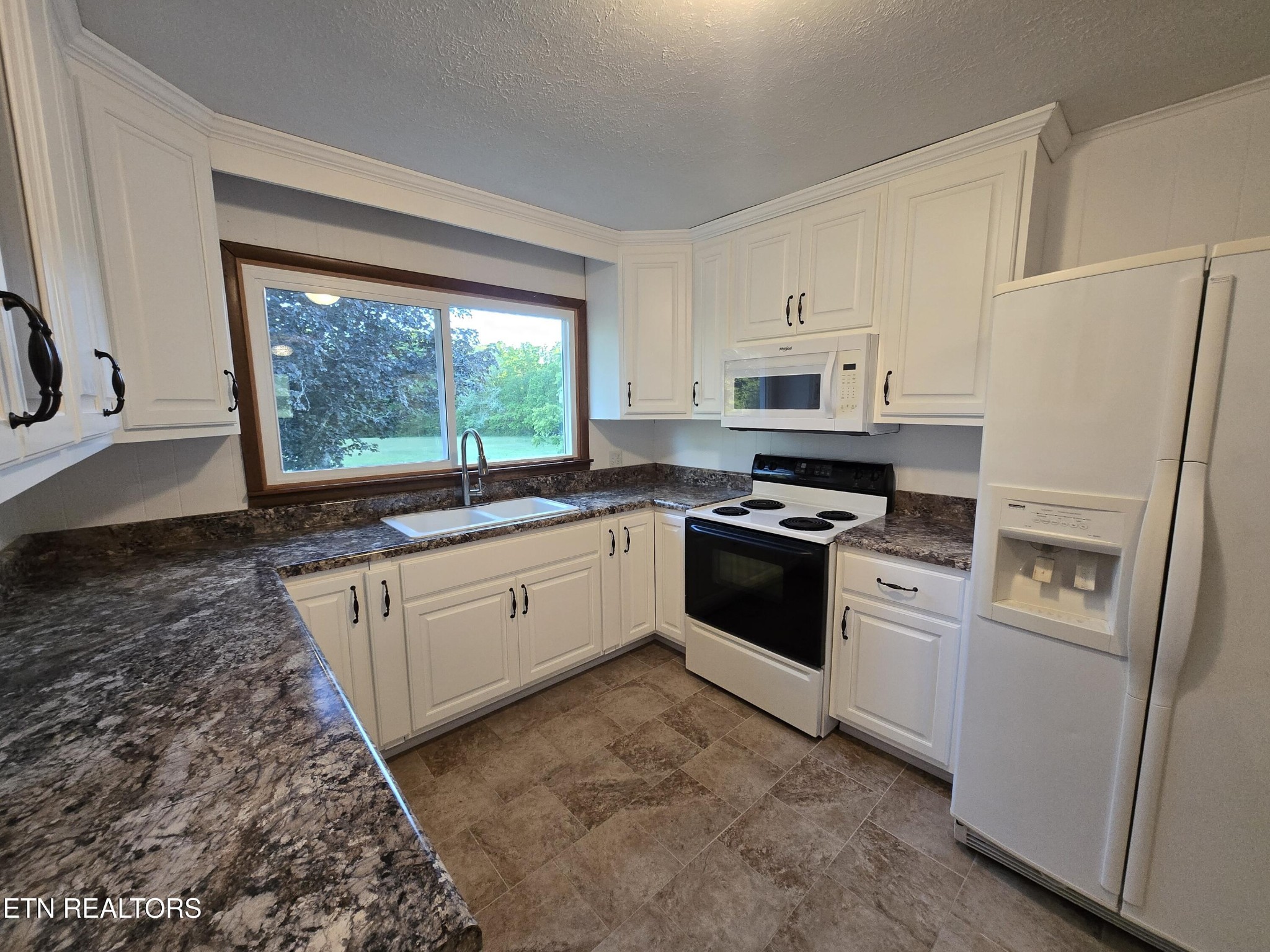 295 Bilbrey Road Crossville, TN 38571 - Photo 10 of 32 a kitchen with granite countertop white cabinets and white appliances