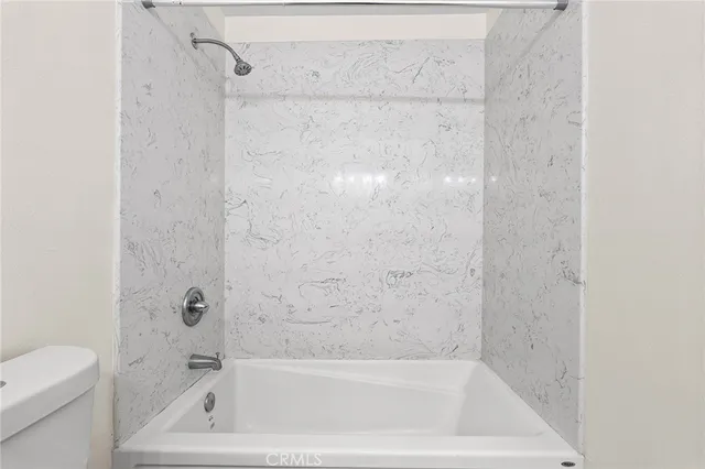 a close view of walk in closet with clothes and shoes