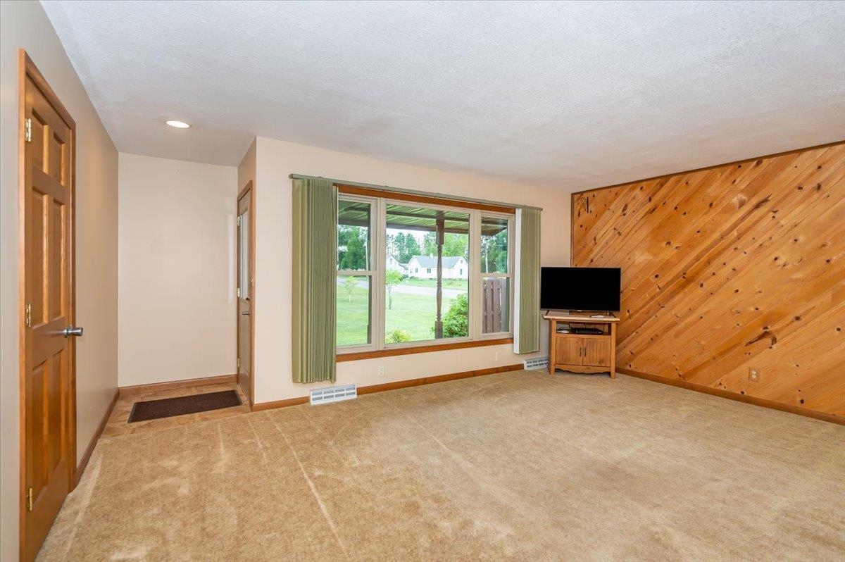 404 Alcohol Road Wrenshall, MN 55797 - Photo 11 of 32 Unfurnished living room with wood walls, light carpet, and a textured ceiling