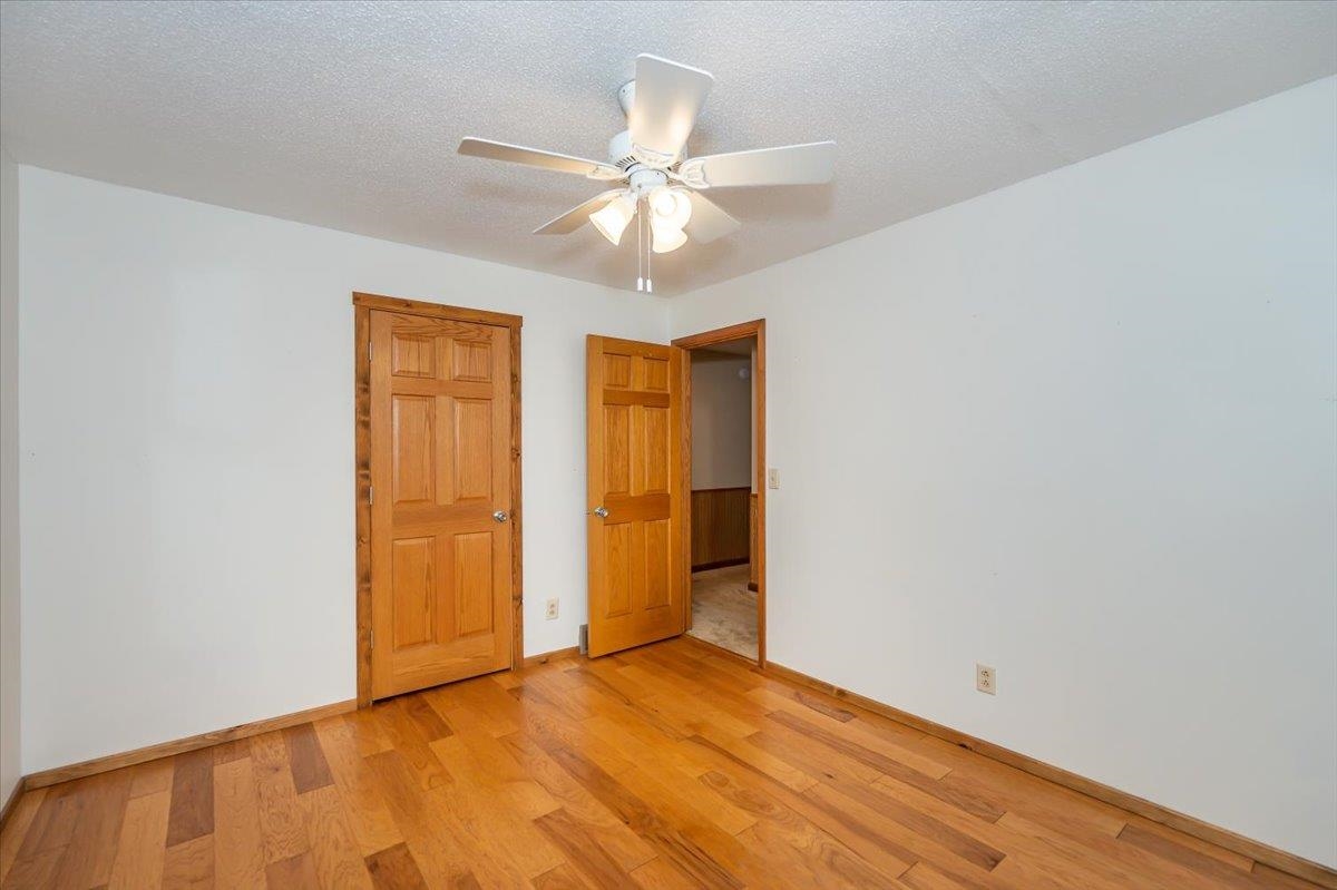 404 Alcohol Road Wrenshall, MN 55797 - Photo 12 of 32 Unfurnished bedroom with light wood finished floors, a textured ceiling, ceiling fan, and a closet