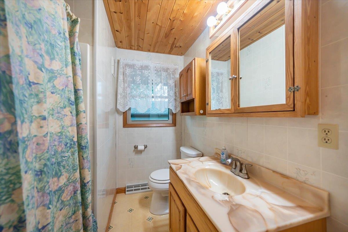 404 Alcohol Road Wrenshall, MN 55797 - Photo 17 of 32 Full bath with tile walls, vanity, wood ceiling, light tile patterned flooring, and curtained shower