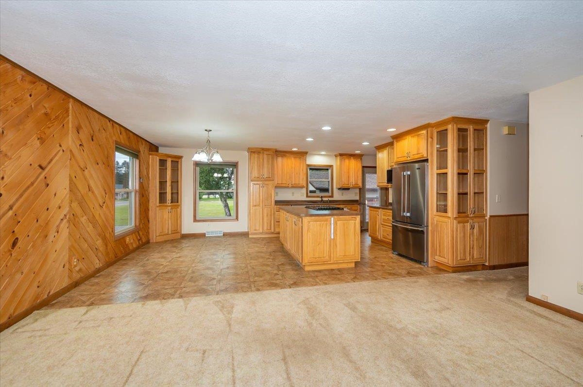 404 Alcohol Road Wrenshall, MN 55797 - Photo 7 of 32 Kitchen featuring wood walls, a chandelier, glass insert cabinets, high quality fridge, and dark countertops