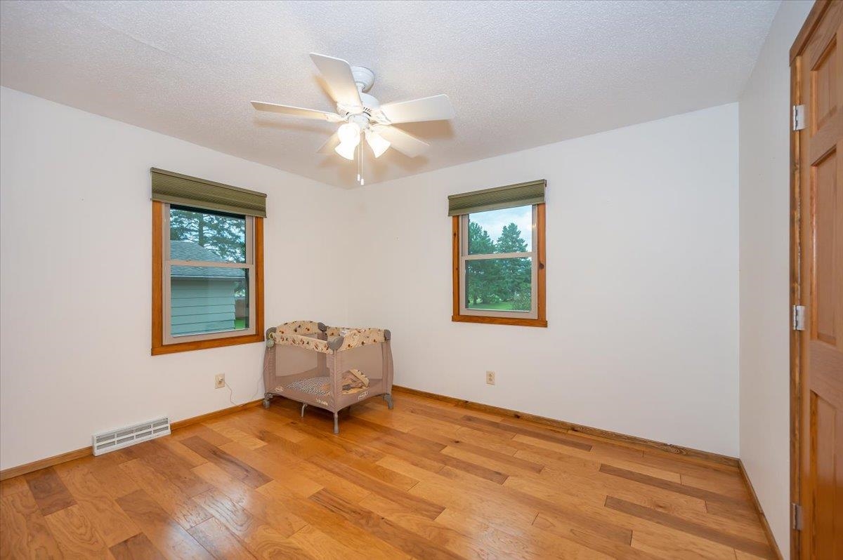 404 Alcohol Road Wrenshall, MN 55797 - Photo 10 of 32 Bedroom with a textured ceiling, multiple windows, a ceiling fan, and light wood-style flooring