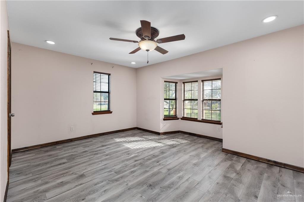310 North Arroyo Boulevard Rio Hondo, TX 78583 - Photo 11 of 31 an empty room with wooden floor chandelier fan and windows